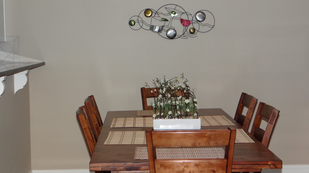 A cozy dining area with a wooden table and chairs, adorned with a modern wall art piece and a centerpiece of potted plants.