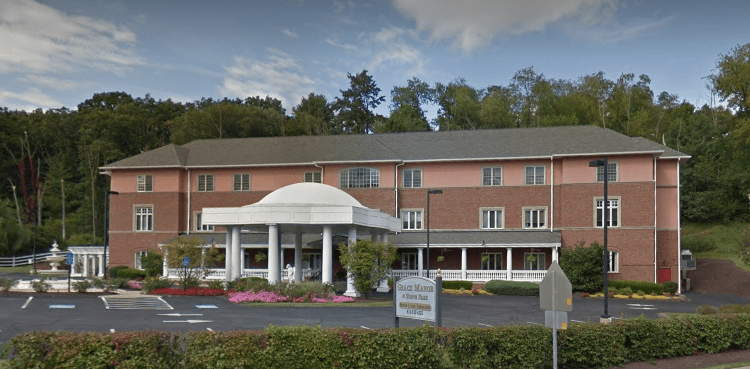 A hotel building with a prominent entrance featuring white columns and a landscaped parking area.