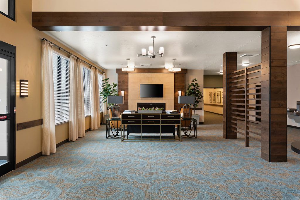 A modern lobby interior featuring a seating area with a television, large windows, and stylish lighting.