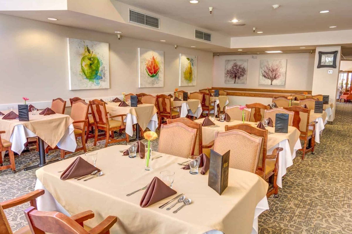 An elegant restaurant dining area with neatly set tables and colorful artwork on the walls.