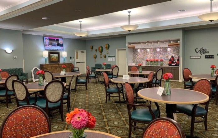 A well-decorated dining area with neatly arranged tables and chairs, adorned with fresh flowers and soft lighting.