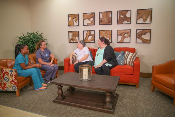 A group of people having a conversation in a cozy living room setting.