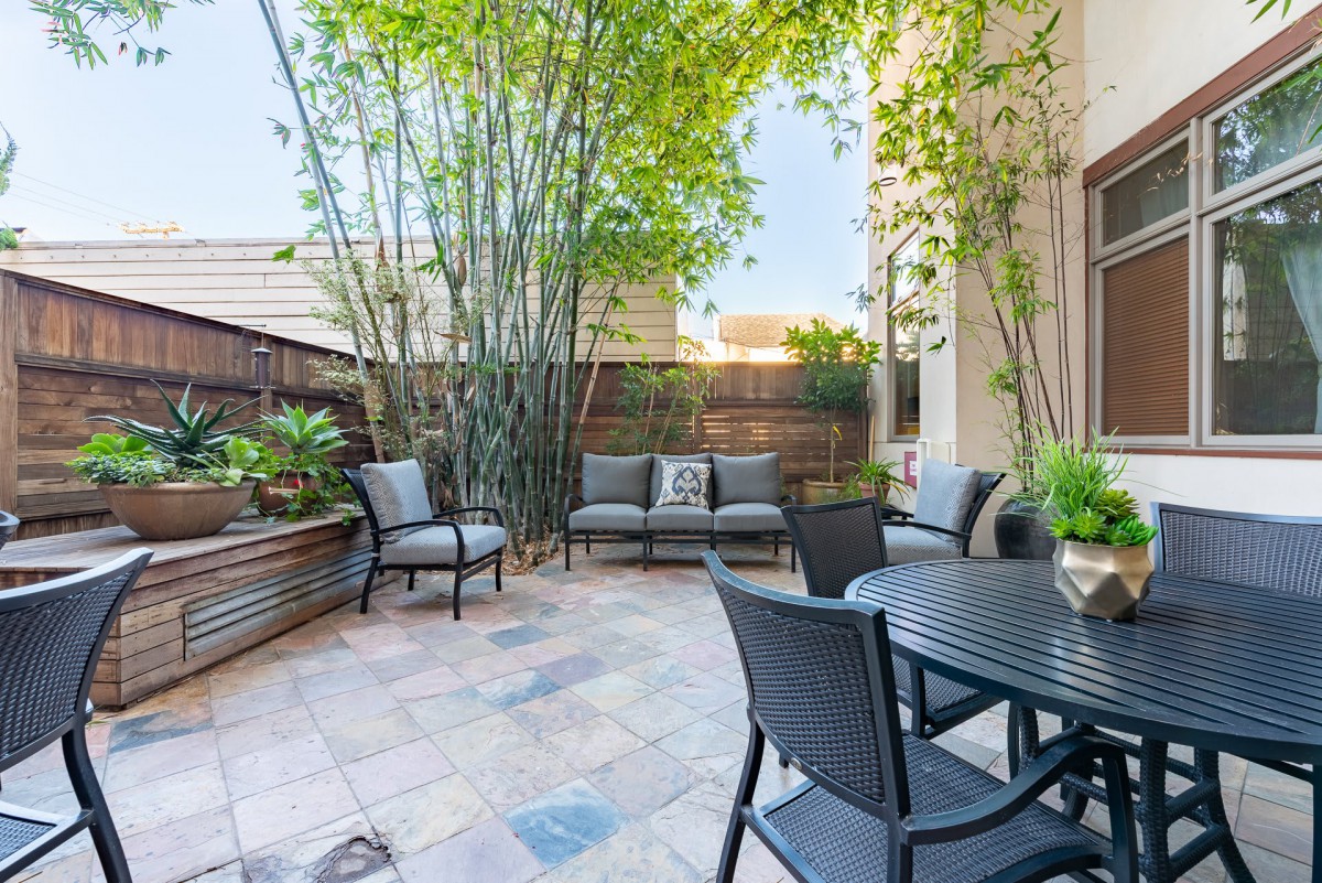 A cozy outdoor patio with seating and lush bamboo plants.