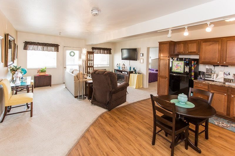 A spacious open-plan living and dining area with a mix of wood flooring and carpet, featuring comfortable seating and modern decor.