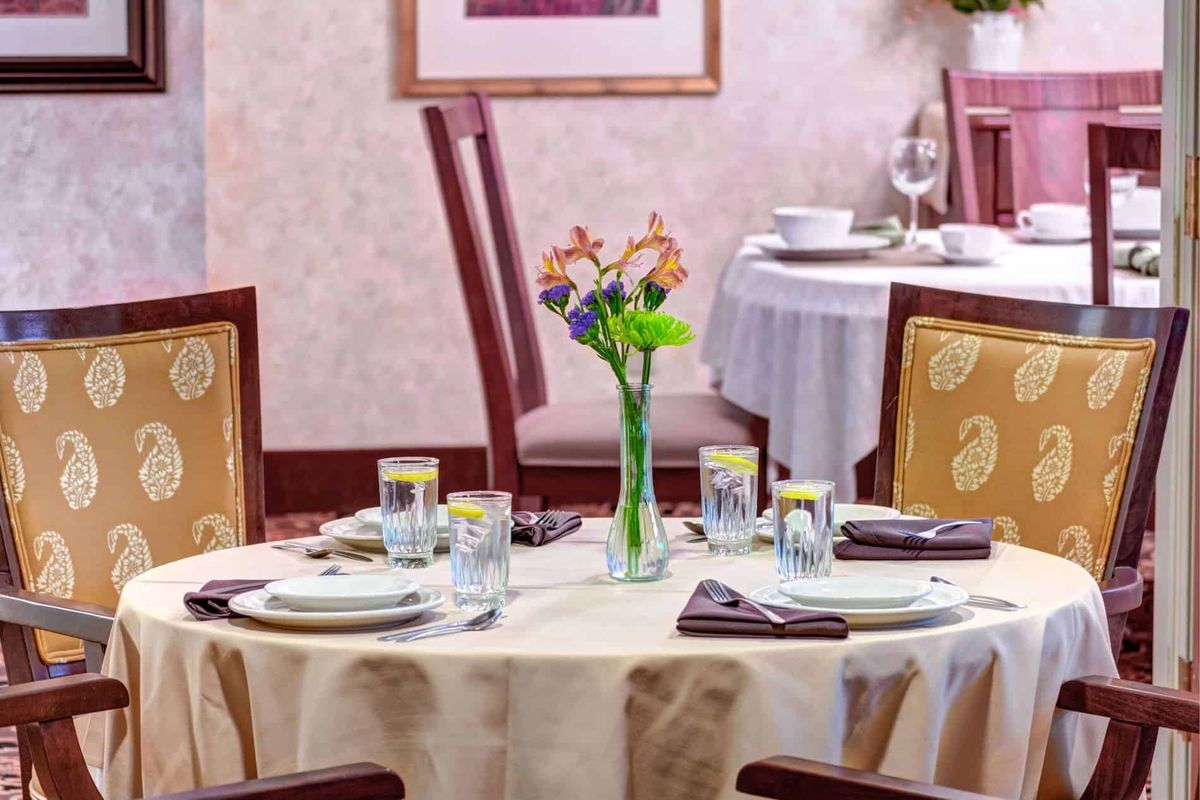 A neatly arranged dining table with floral centerpiece, ready for guests at a restaurant.