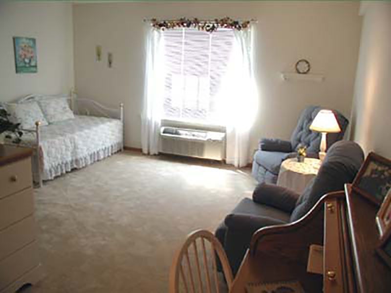 A cozy bedroom with a single bed, armchair, and a window with curtains.