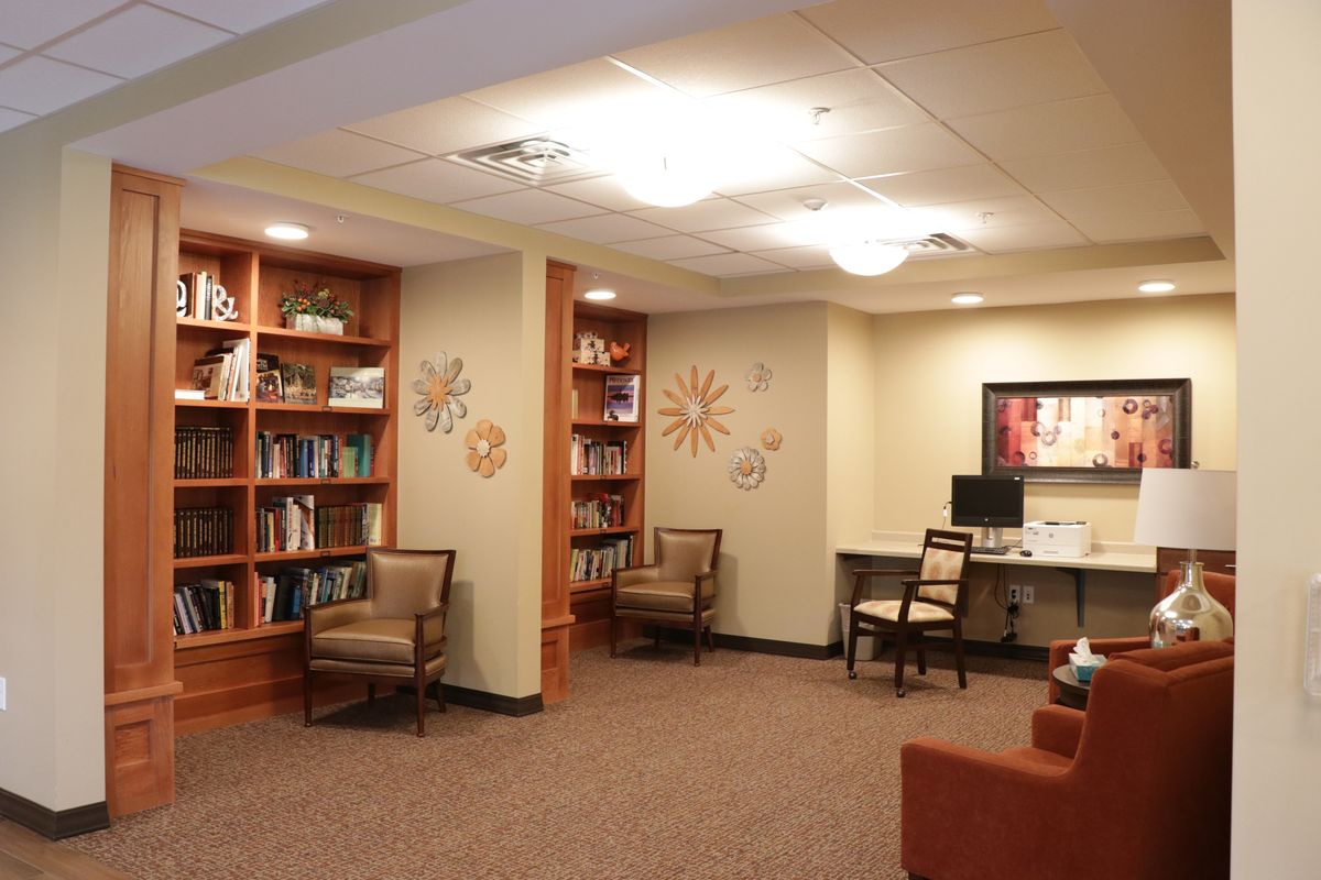 A cozy library space with bookshelves, comfortable chairs, and a computer desk.