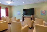 A modern meeting room with comfortable chairs and a large TV screen.