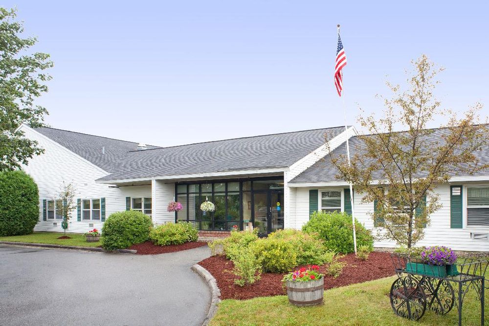 A well-maintained building entrance with lush landscaping and an American flag.