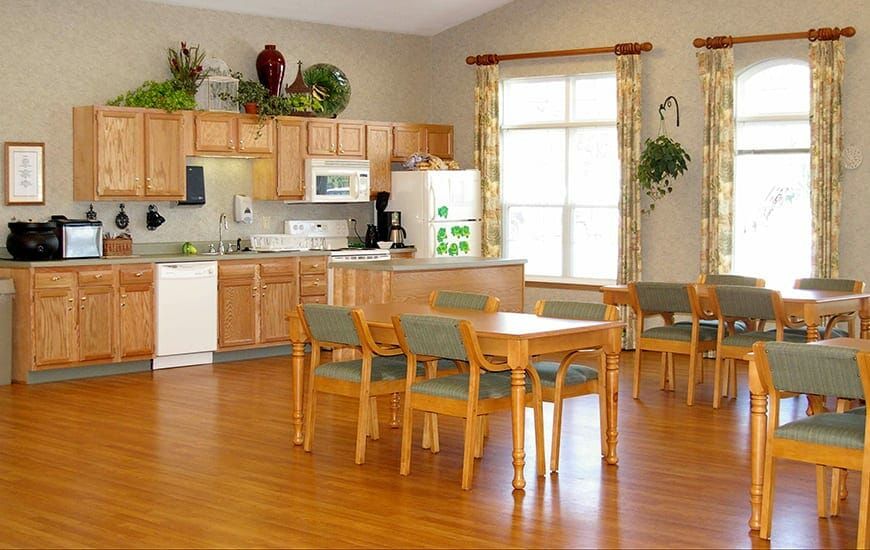 A cozy kitchen and dining area with wooden cabinets, a table, chairs, and home appliances.