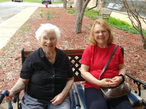 Two women enjoying a sunny day in the park, sharing smiles on a bench.