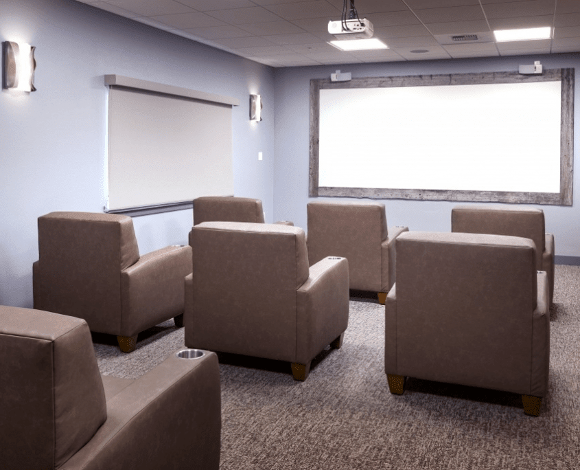 A home theater room with comfortable seating and a large projector screen.