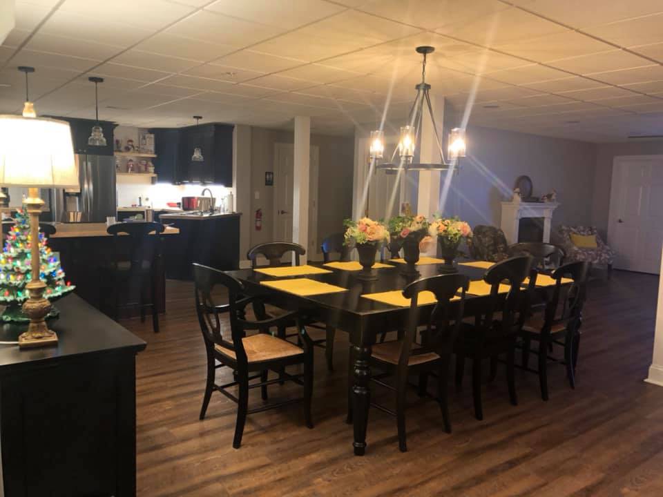 A modern dining area with a large table, elegant lighting, and a cozy kitchen space.
