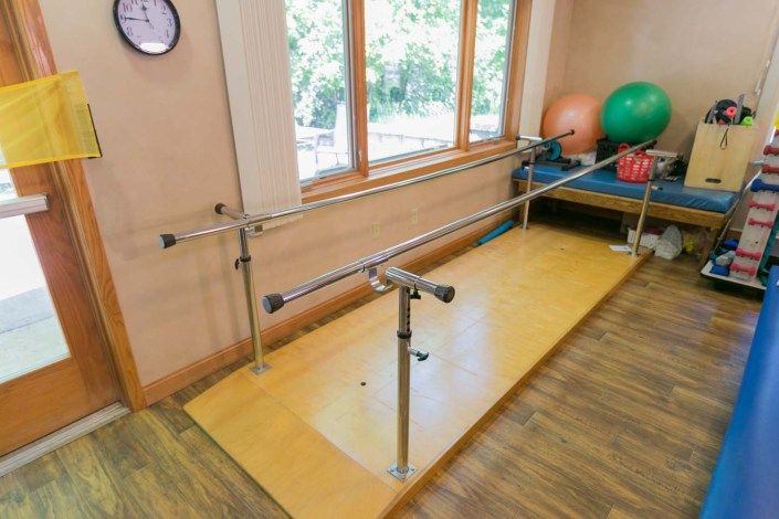A therapy room equipped with parallel bars for physical rehabilitation exercises.