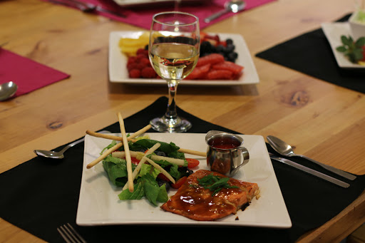 A beautifully plated salmon dinner with a side of fresh salad and a glass of white wine.