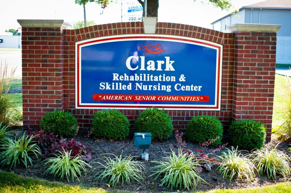 Sign for Clark Rehabilitation & Skilled Nursing Center surrounded by landscaped gardens.