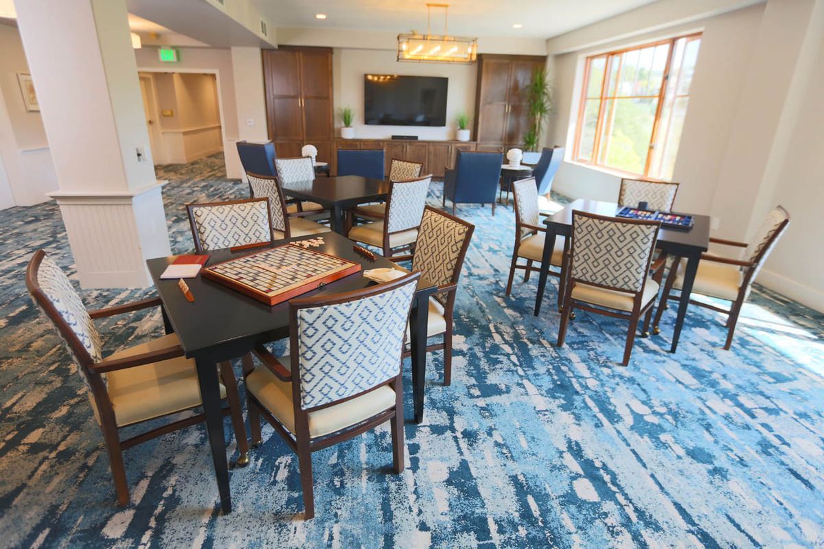A comfortable lounge area with tables, chairs, a game board, and a television.