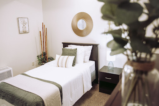 A serene and minimalist bedroom featuring a neatly made twin bed with green accents, complemented by simple decor.