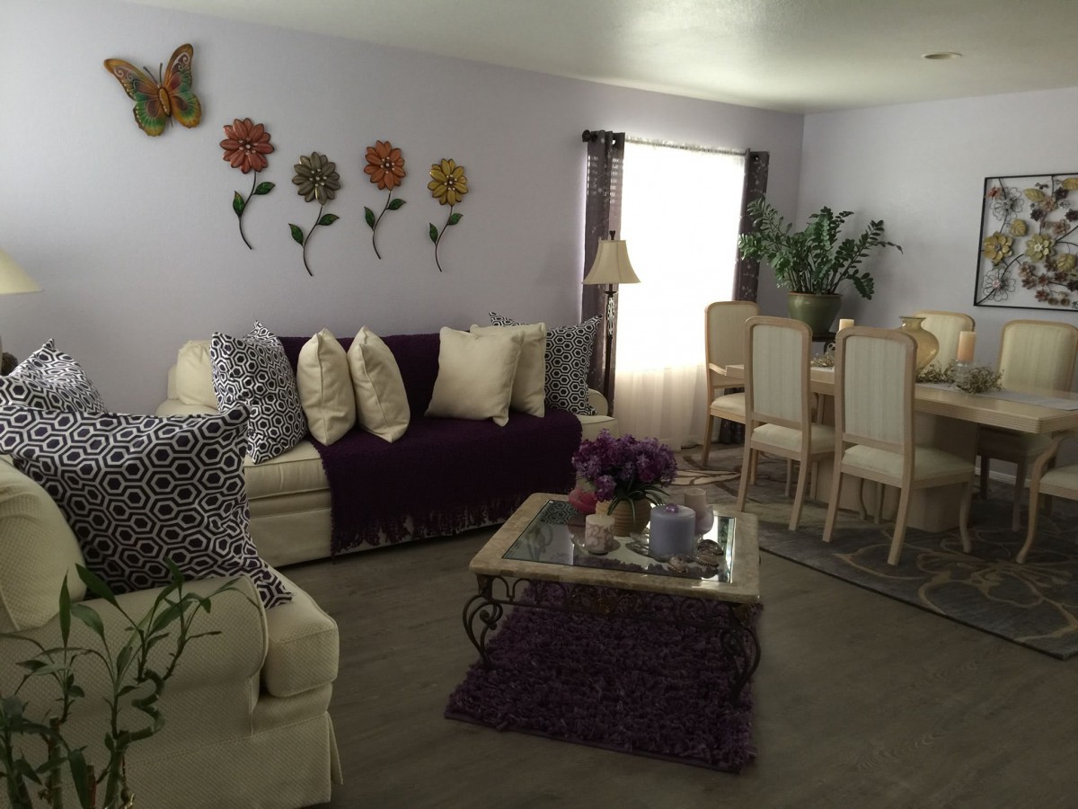 A cozy living room with a sofa, coffee table, dining area, and decorative wall art.