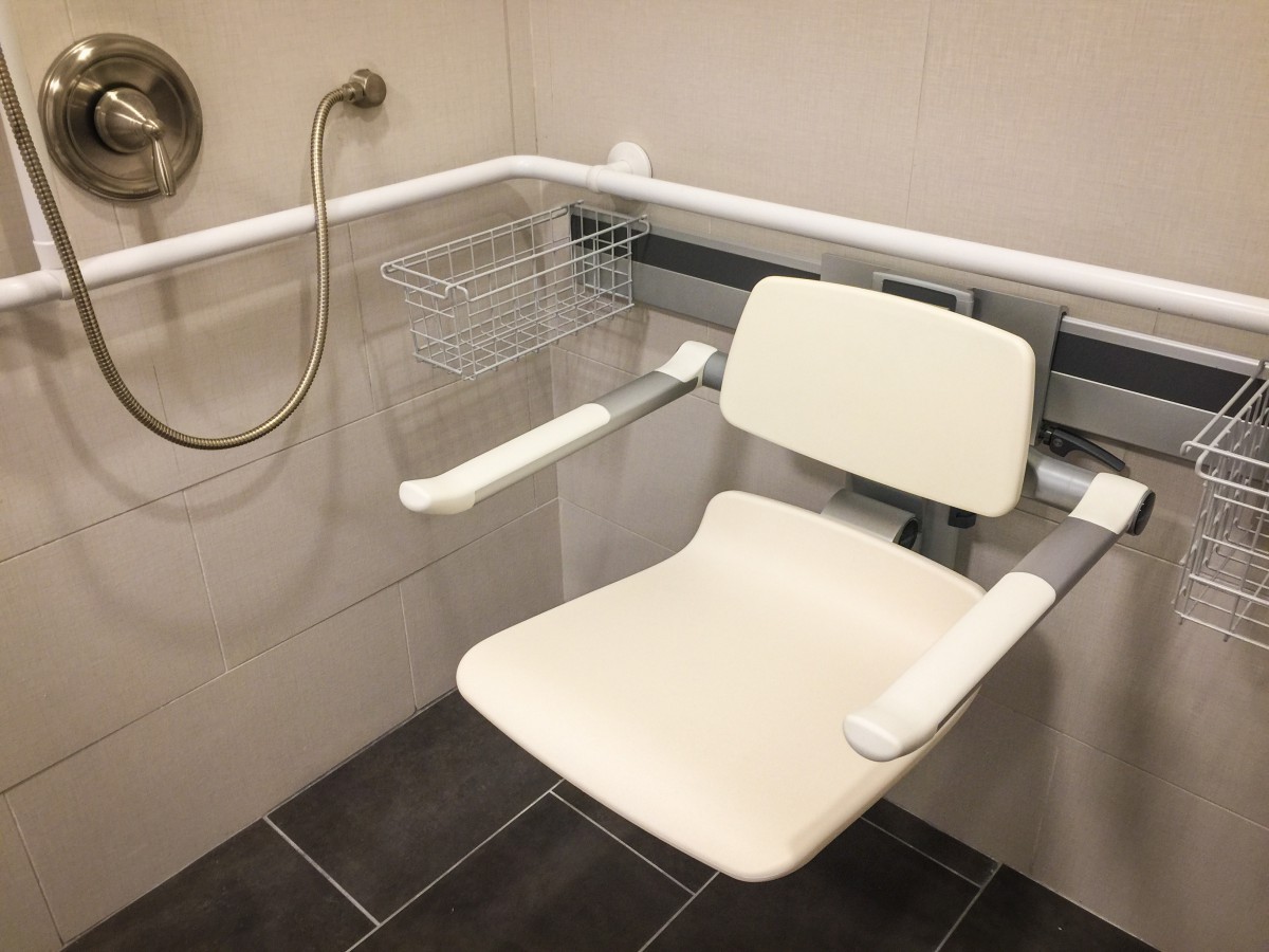 An accessible shower area featuring a folding chair and grab bars for safety.