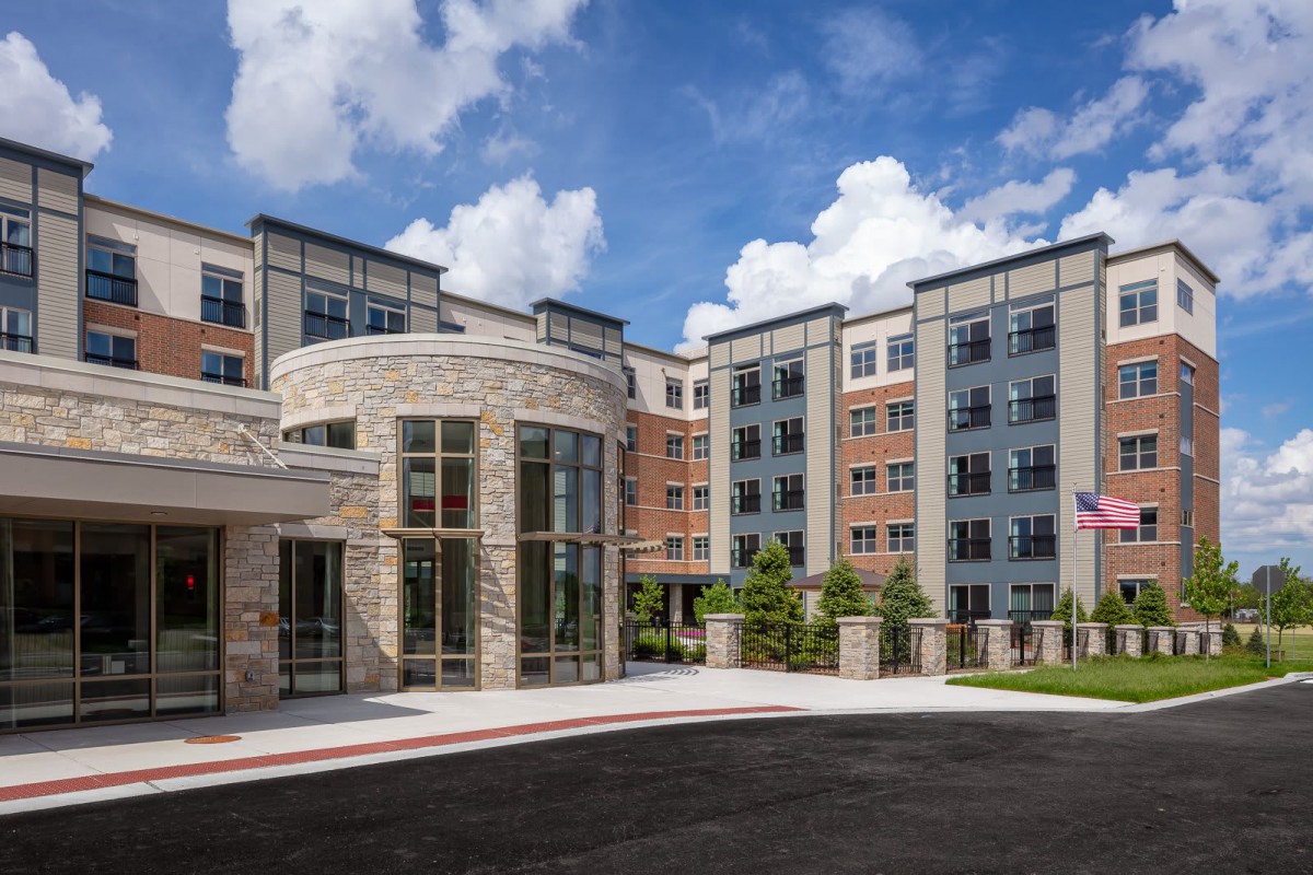 A modern residential building with a stone facade under a clear blue sky.