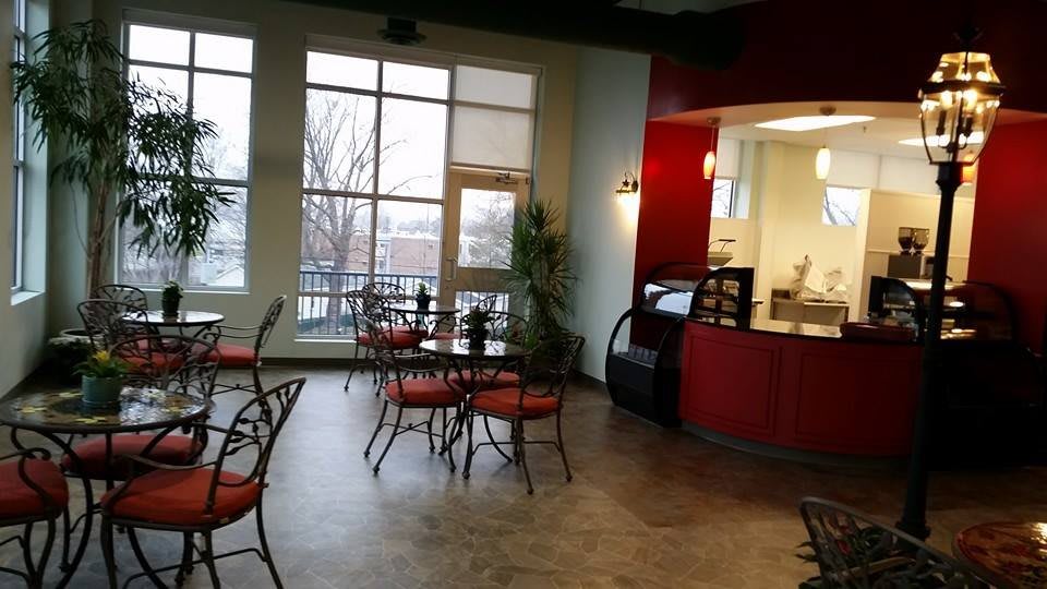 A modern cafe interior with empty tables and chairs, featuring large windows and red accents.