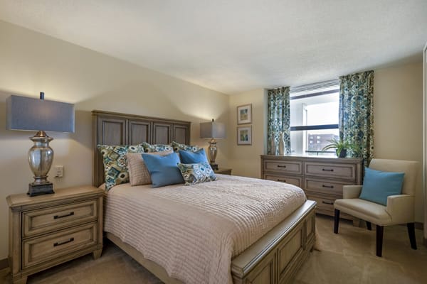 A cozy bedroom with a wooden bed frame, colorful pillows, and matching furniture.