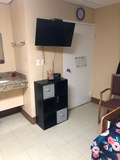 A simple setup in a hotel room featuring a television, storage unit, and a seating area.