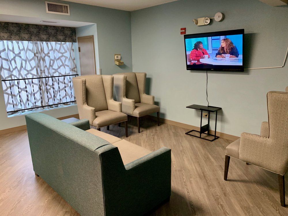 A cozy living room with a television, comfortable seating including a sofa and chairs.