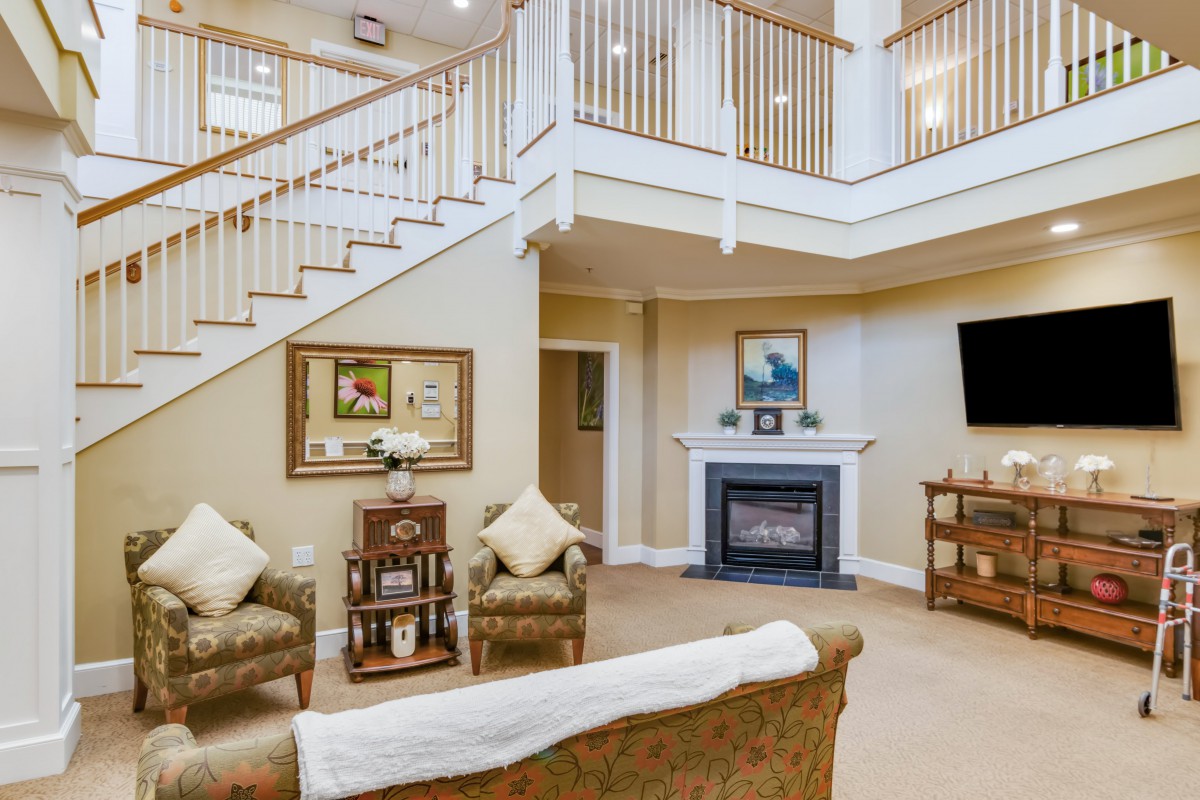 A cozy living room with a fireplace, elegant staircase, and comfortable seating.