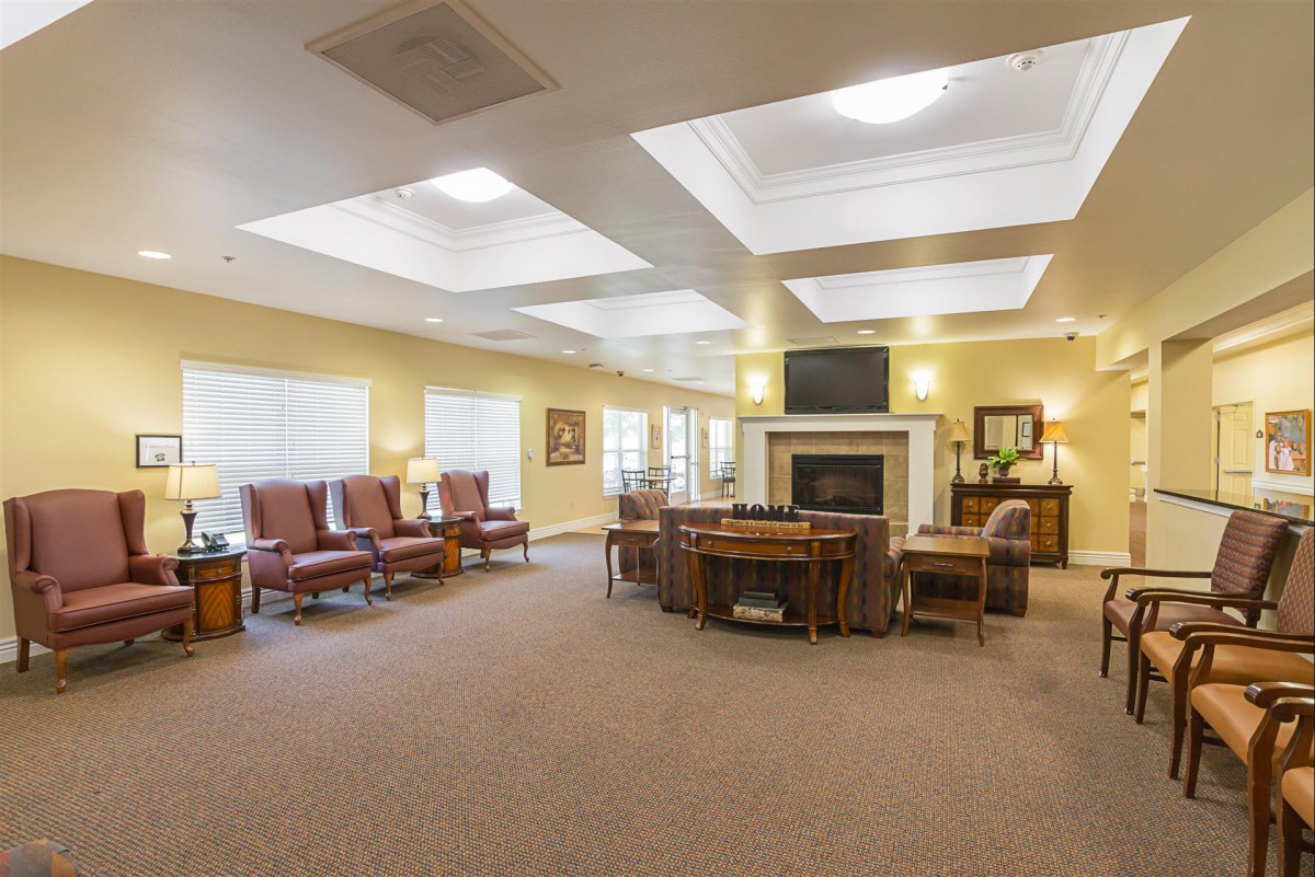 A spacious and well-lit living area featuring multiple seating arrangements and a central fireplace.