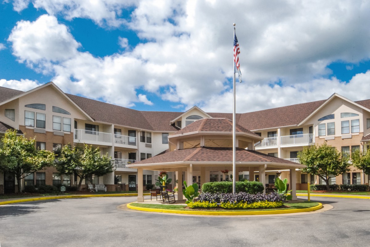A residential building with a circular driveway and an American flag flying in front.