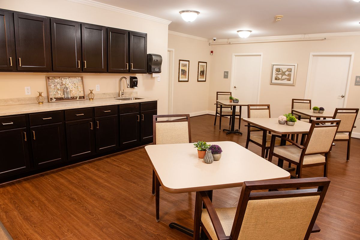 A neatly arranged dining area with tables, chairs, and cabinets in a well-lit indoor space.