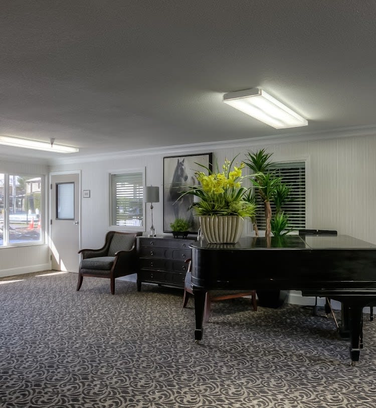 A well-furnished lobby area featuring a grand piano, comfortable seating, and decorative plants.