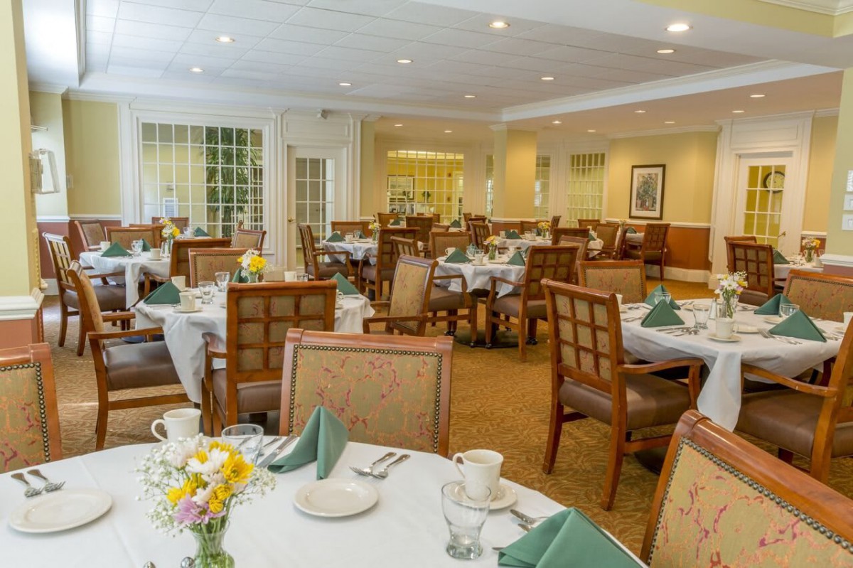 A formal dining room set up with tables and chairs, featuring neatly arranged table settings.