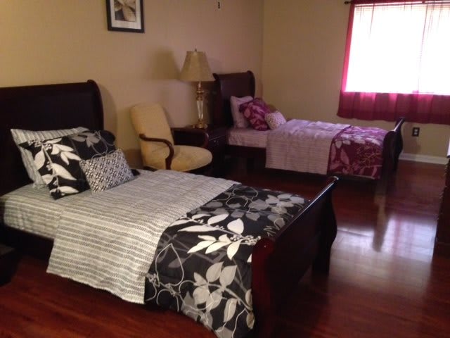 A cozy bedroom with a double bed and a single bed, featuring wooden flooring and warm lighting.
