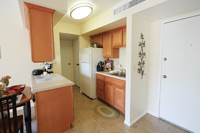A compact kitchen with wooden cabinets, a refrigerator, and a countertop.