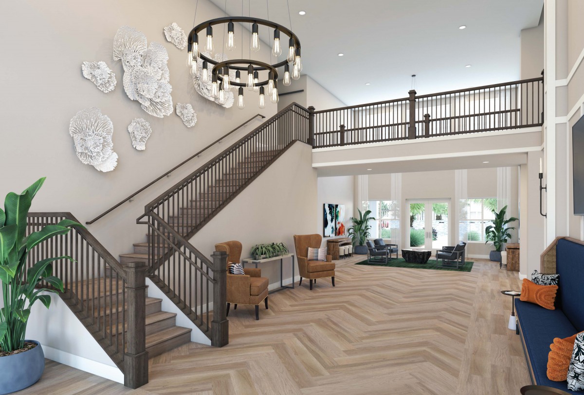A modern lobby with a grand staircase, elegant chandelier, and comfortable seating area.