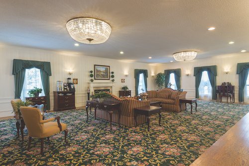 A traditionally decorated living room with chandeliers and floral carpet.