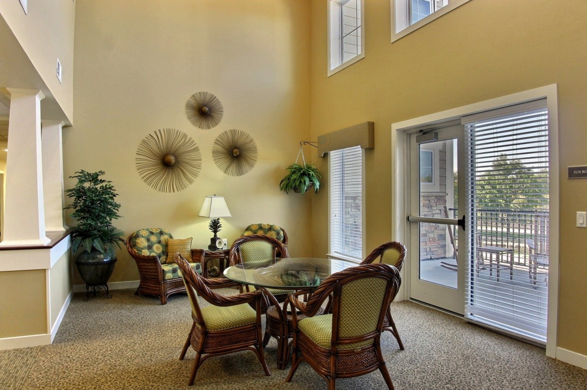 A cozy living room with a table and chairs set, adorned with elegant decor and plants.
