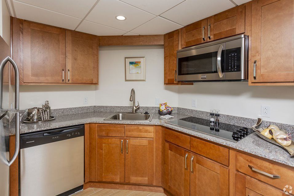 A modern kitchen with wooden cabinets, a sink, and built-in appliances including a microwave.