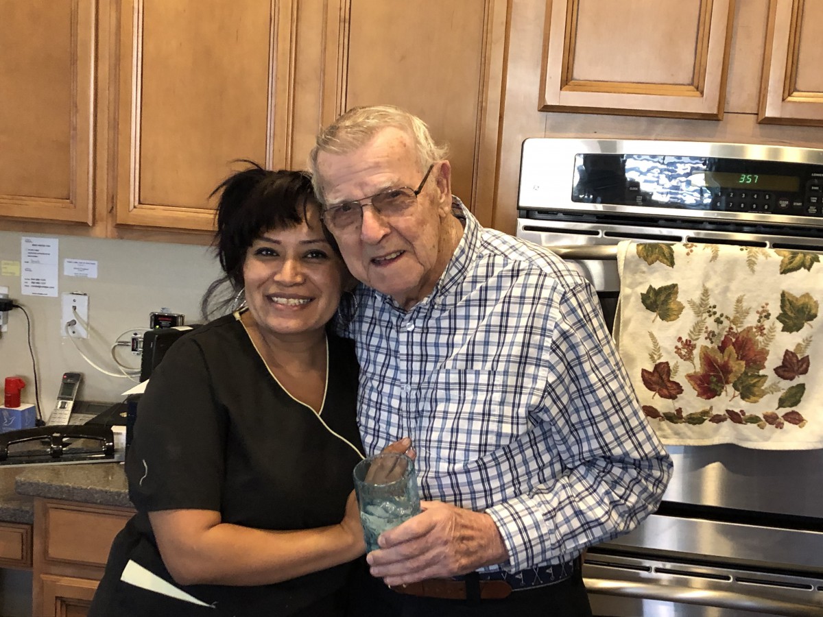 Two people smiling and hugging in a kitchen.