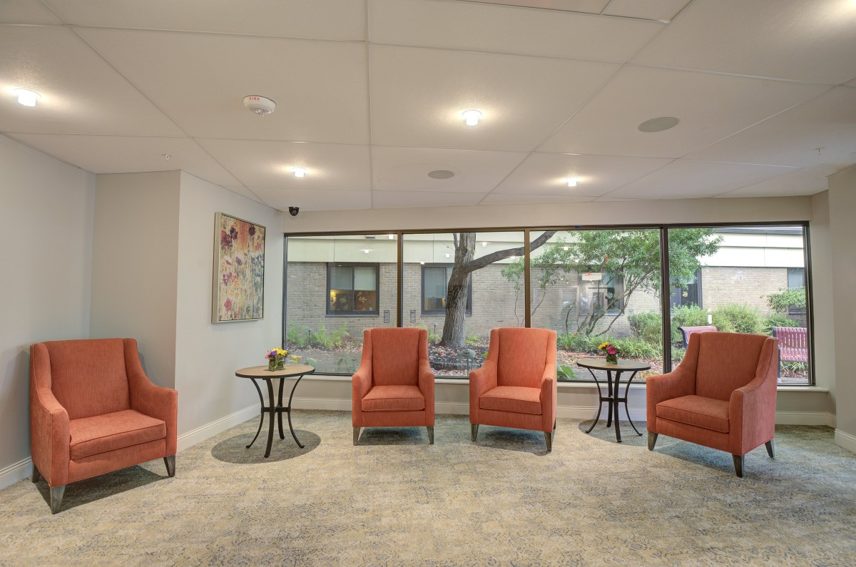 A modern waiting room with orange chairs and large windows.