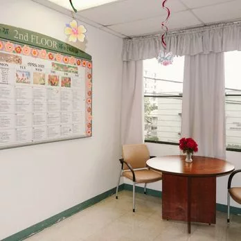 A small waiting area with a round table, two chairs, and a poster on the wall.