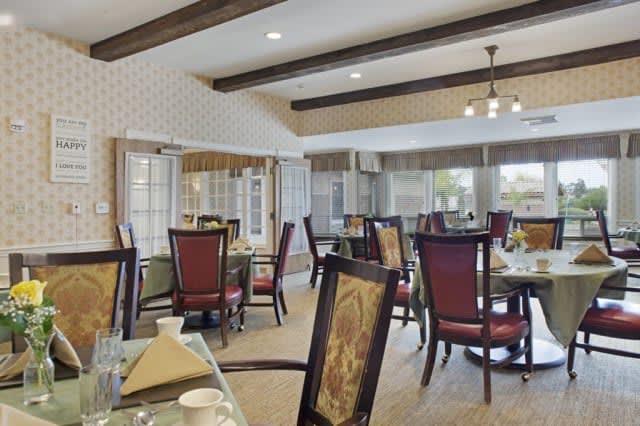 A spacious dining area with elegantly set tables and chairs, featuring a warm and inviting decor.