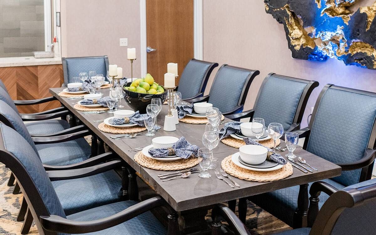 A stylishly set dining table with blue chairs and a centerpiece fruit bowl, creating an elegant ambiance.