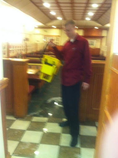 An employee addresses a spill in the restaurant while holding a caution sign.