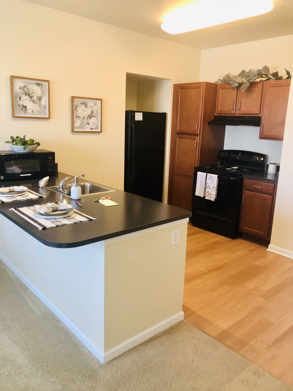 A modern kitchen with wooden cabinets, black appliances, and a countertop island.