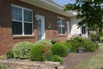 A residential brick house with well-maintained garden landscaping.