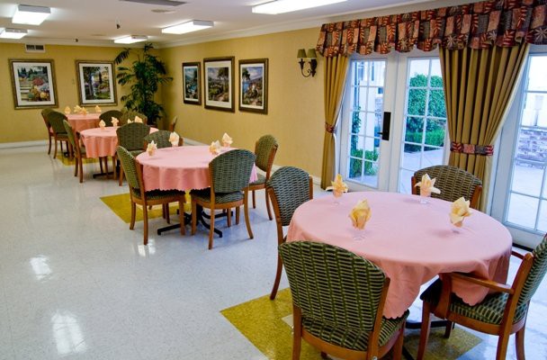 A well-arranged dining area with round tables covered in pink tablecloths, surrounded by chairs and decorated with art on the walls.
